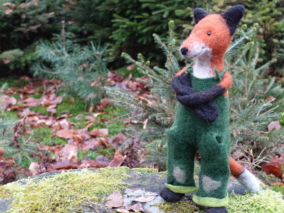 Filzfuchs mit grüner Latzhose im Wald
