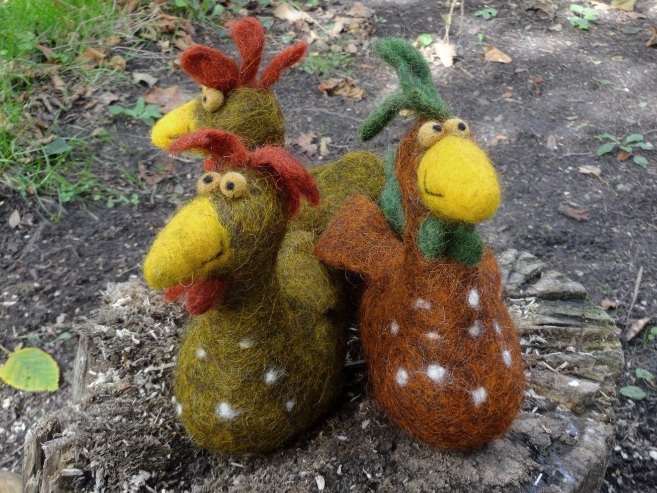 Drei gefilzte bunte Hühner im Garten
