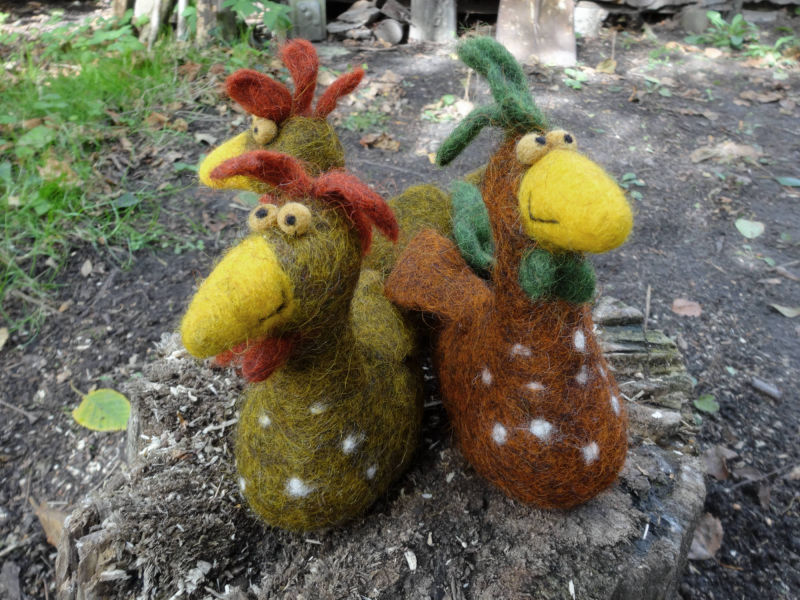 Drei bunte gefilzte Hühner im Garten