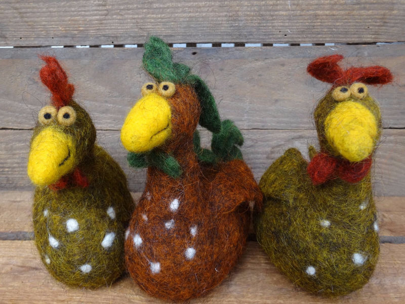 Drei gefilzte bunte Hühner in einer Holzkiste