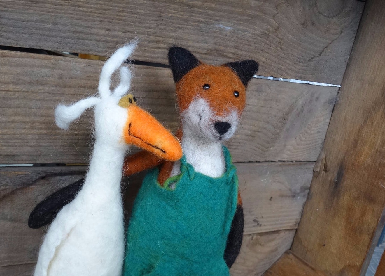 Ein gefilzter Fuchs mit grüner Latzhose und eine weiße gefilzte Gans