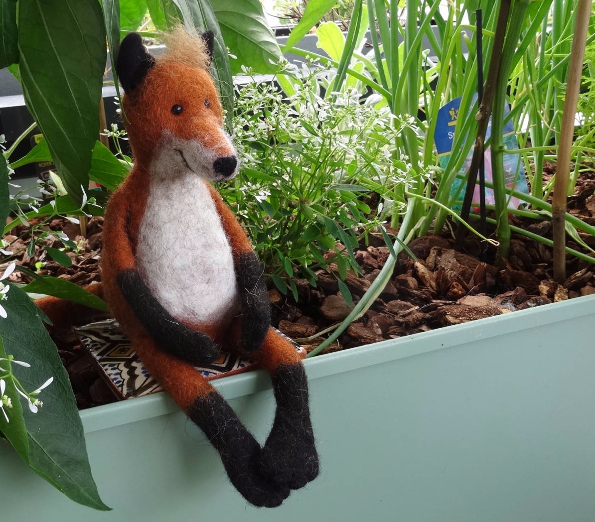Gefilzter Fuchs sitzt auf Blumenkasten